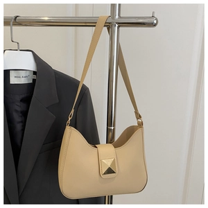 Détail du sac croissant beige avec boucle dorée sur un fond de veste grise moderne