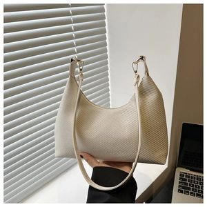 Macro detail of beige woven texture and leather strap on a summer hobo shoulder bag