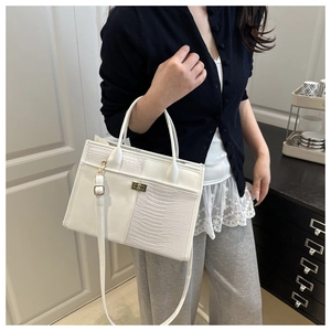 Close-up of white faux crocodile leather texture and golden metal twist lock on tote bag