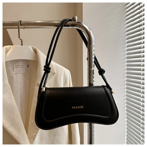 Close-up of minimalist black handbag with golden brand logo and knotted handle details