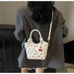 Détail du sac hobo blanc avec imprimé cerises rouges et son pendentif assorti