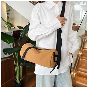 Detail view of ginger yellow cylinder crossbody bag with black nylon shoulder strap