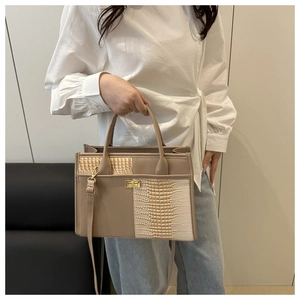Close-up of golden twist-lock closure and crocodile-embossed leather texture on tote bag
