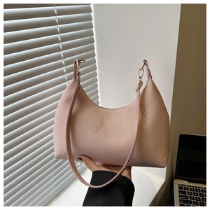 Detailed view of pink woven texture shoulder bag with gold hardware on a desk