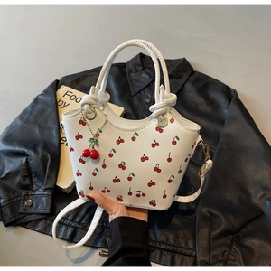 Détail du sac à main blanc avec imprimé cerise rouge et breloque cerise en relief