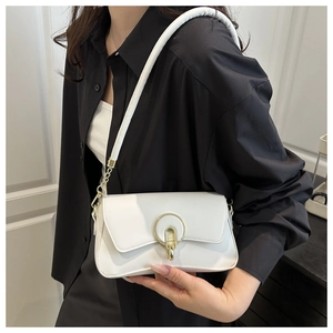Detailed view of a white minimalist small square bag with a prominent gold round buckle