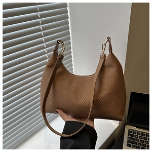 Detailed shot of dark brown woven texture handbag with golden metal clasp and strap