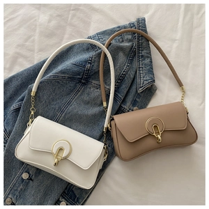 Detail of white and beige shoulder bags with gold u-shaped metal buckles and chain straps
