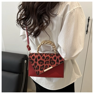 Modische rote Umhängetasche mit Leopardenmuster und goldenem gedrehtem Metallgriff am Model
