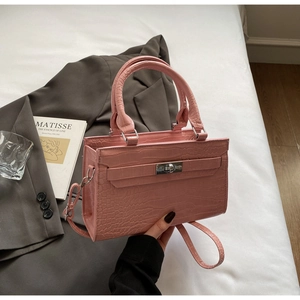 Detailed view of pink croc-effect handbag with silver twist lock and tubular handles