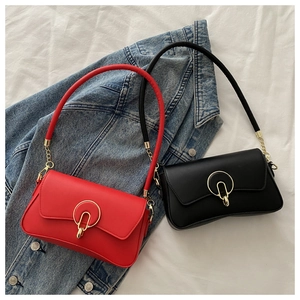 Detail of red and black PU leather crossbody bags with golden circular metal buckle on top