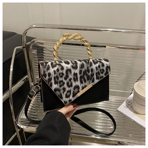 Detail der Klappe mit Leopardenmuster und elegantem goldenem Metallgriff an schwarzer Tasche