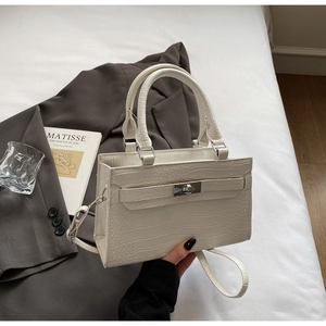Close-up of white crocodile pattern leather bag with silver metal swivel lock and handle