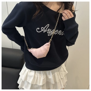 Detailed view of pink croissant crossbody bag with golden chain strap on model