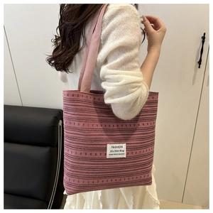 Detail of pink striped woven tote bag featuring a stitched fashion label and texture