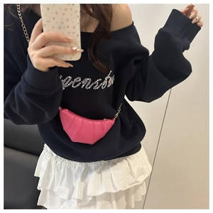 Detailed view of pink pleated croissant bag with gold chain strap worn by a model