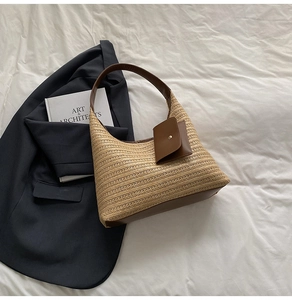Detail of hobo straw bag with brown leather trim and hanging mini pouch accessory