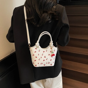 Sac seau blanc à imprimé cerises avec poignée tressée et charm mignon sur bois