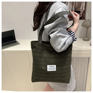 Detail of dark green canvas tote bag with textured stripes and stylish side profile view
