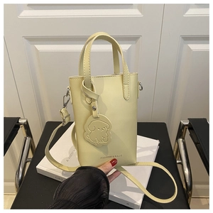 Détail du sac seau en similicuir jaune pâle avec breloque chien et boucles argentées