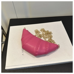 Detail of rose red croissant bag featuring layered stitching and a gold chain strap