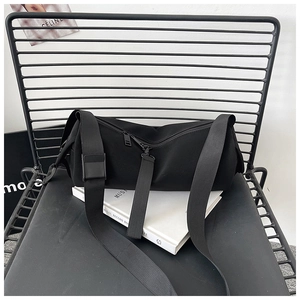 Detail of black cylindrical crossbody bag with dual zippers and adjustable wide strap
