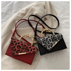 Detail der Handtasche mit Leopardenmuster und goldenem Metallgriff in Rot und Schwarz