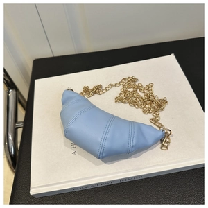 Macro view of light blue quilted leather croissant bag with delicate gold chain strap