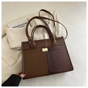 Detail of coffee brown tote featuring crocodile texture stitching and golden twist lock