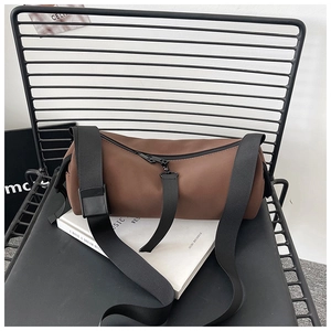 Macro detail of brown frosted PU barrel bag with wide adjustable black nylon strap