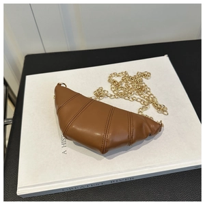 Detailed view of brown croissant bag featuring pleated faux leather and gold chain strap