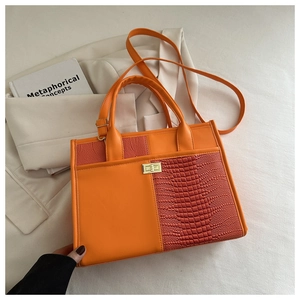 Detail of orange crocodile pattern tote bag with gold twist lock and smooth leather patchwork