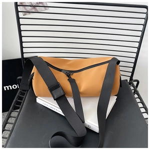 Detail of a bright yellow cylindrical barrel bag with black nylon straps and zipper view