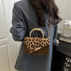 Umhängetasche mit Leopardenmuster und goldenem Knotengriff am blauen Blazer