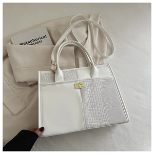 Detail of crocodile pattern stitching on a cream leather tote bag with gold swivel lock