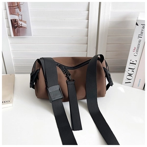 Macro detail of brown matte PU cylinder bag with black wide nylon strap and buckle