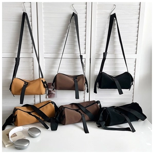 Detailed view of minimalist cylindrical canvas bags with broad straps and zip pullers
