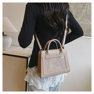Beige crossbody bag with clear display window shown in a stylish minimalist interior setting