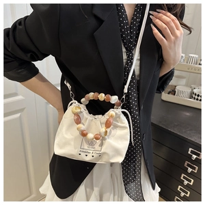 Detail of white canvas drawstring bucket bag with marble bead handle and branding