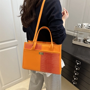 Orange croc-embossed patchwork handbag with gold clasp shown on a crossbody model