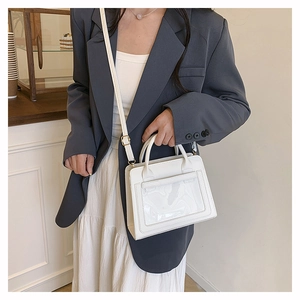 White minimalist crossbody bag with clear PVC pocket shown on model in cafe