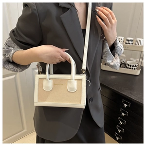 Detail of hand-woven beige tote bag with white leather trim and logo lettering