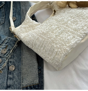 Détail du sac à main plissé blanc avec texture à bulles et fermoirs métalliques dorés