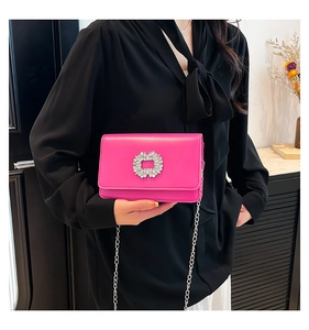 Detail of elegant magenta crossbody bag with sparkling rhinestone buckle on satin-finish PU