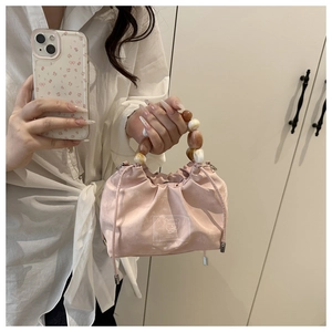 Detailed view of pink pleated bucket bag with amber bead handle and cartoon bear print