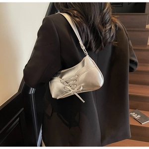 Dettaglio della borsa baguette argento con fiocco decorativo indossata da modella