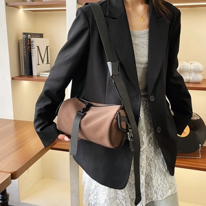 Brown frosted PU cylinder crossbody bag with black wide strap shown on a fashion model