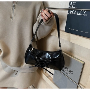 Dettaglio della borsa baguette in vernice nera con decorazione a nastro stringato stile