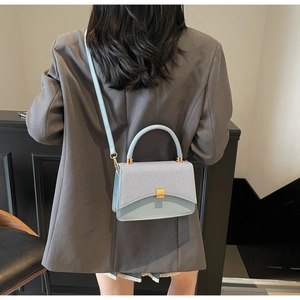 Detailed view of light blue crossbody bag with mixed texture and gold metal buckle