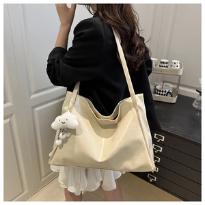 Détail du sac cabas brillant crème avec breloque nuage porté par un mannequin
